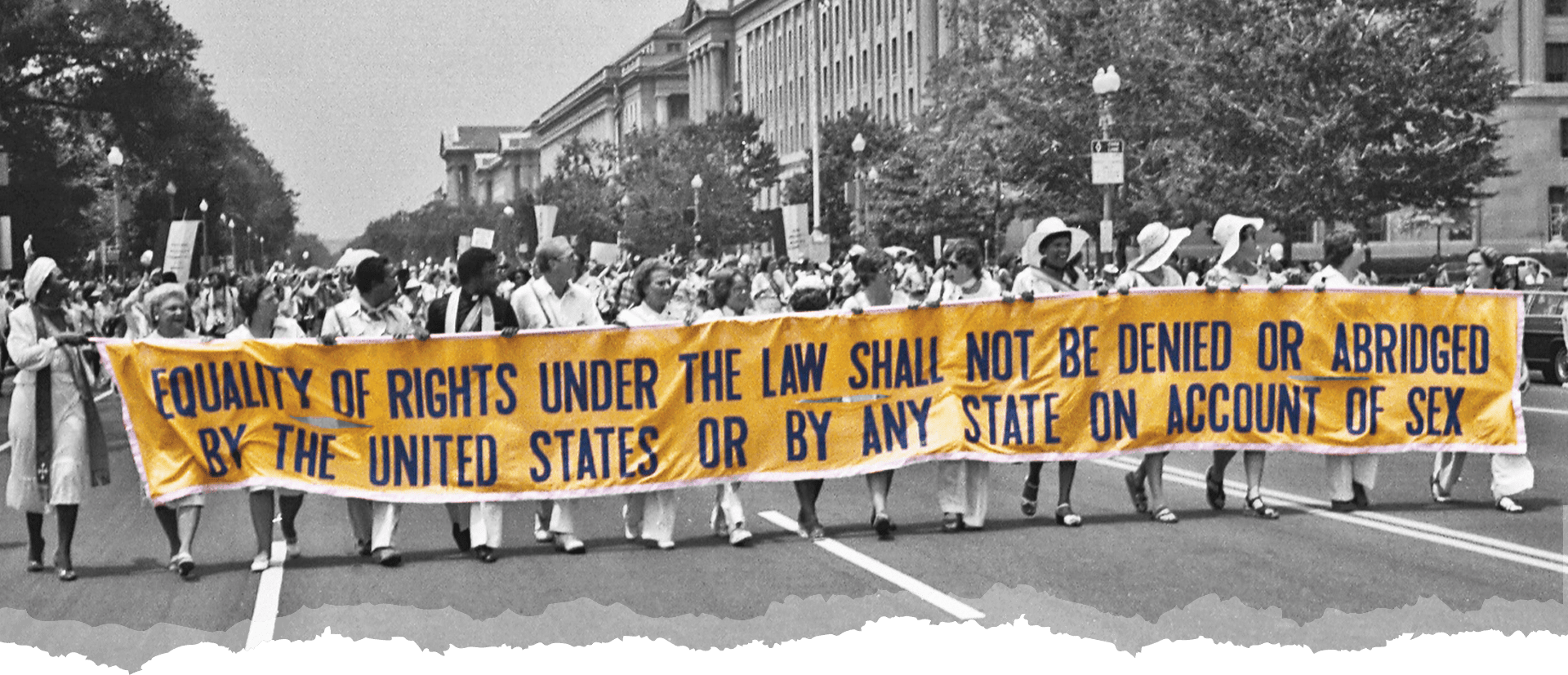 Image of marchers carrying a banner that reads: Equality of Rights Under the Law Shall Not Be Denied or Abridged by the United States or by Any State on Account of Sex
